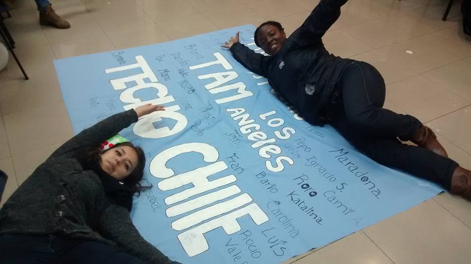 Two young girls lying on top of a blue poster in Chile.