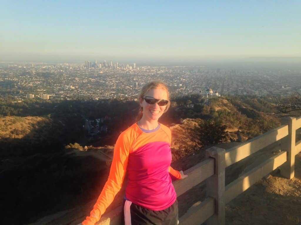 A young traveller standing in the mountains that overlooks a city.