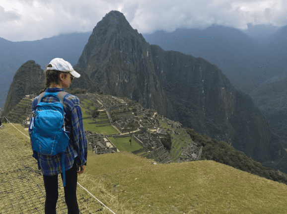 Woman wearing a hat and backpack, looking over Machu Picchu, Peru